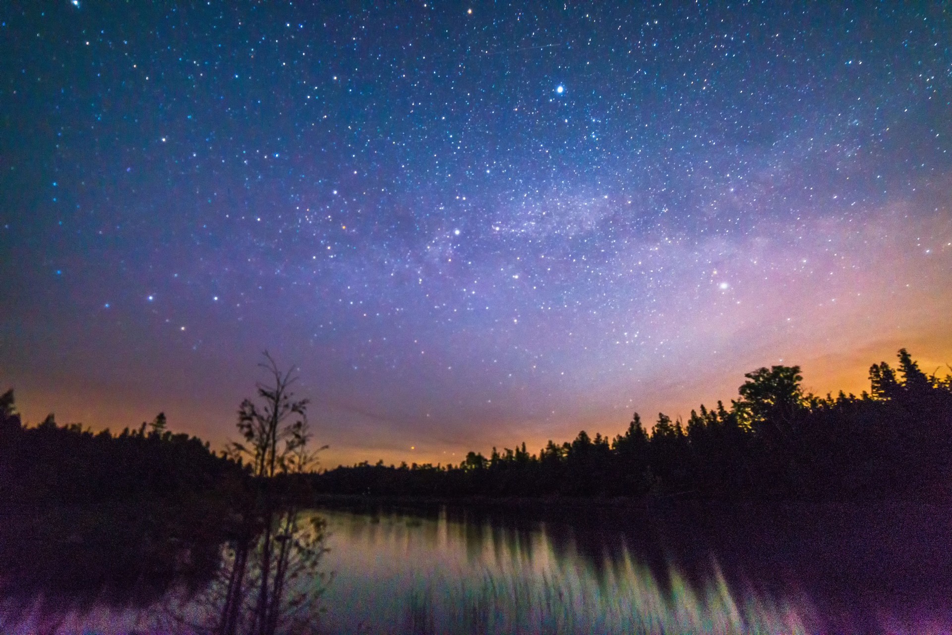 Colorful moonrise over a still river at night with milky way, stars and night sky